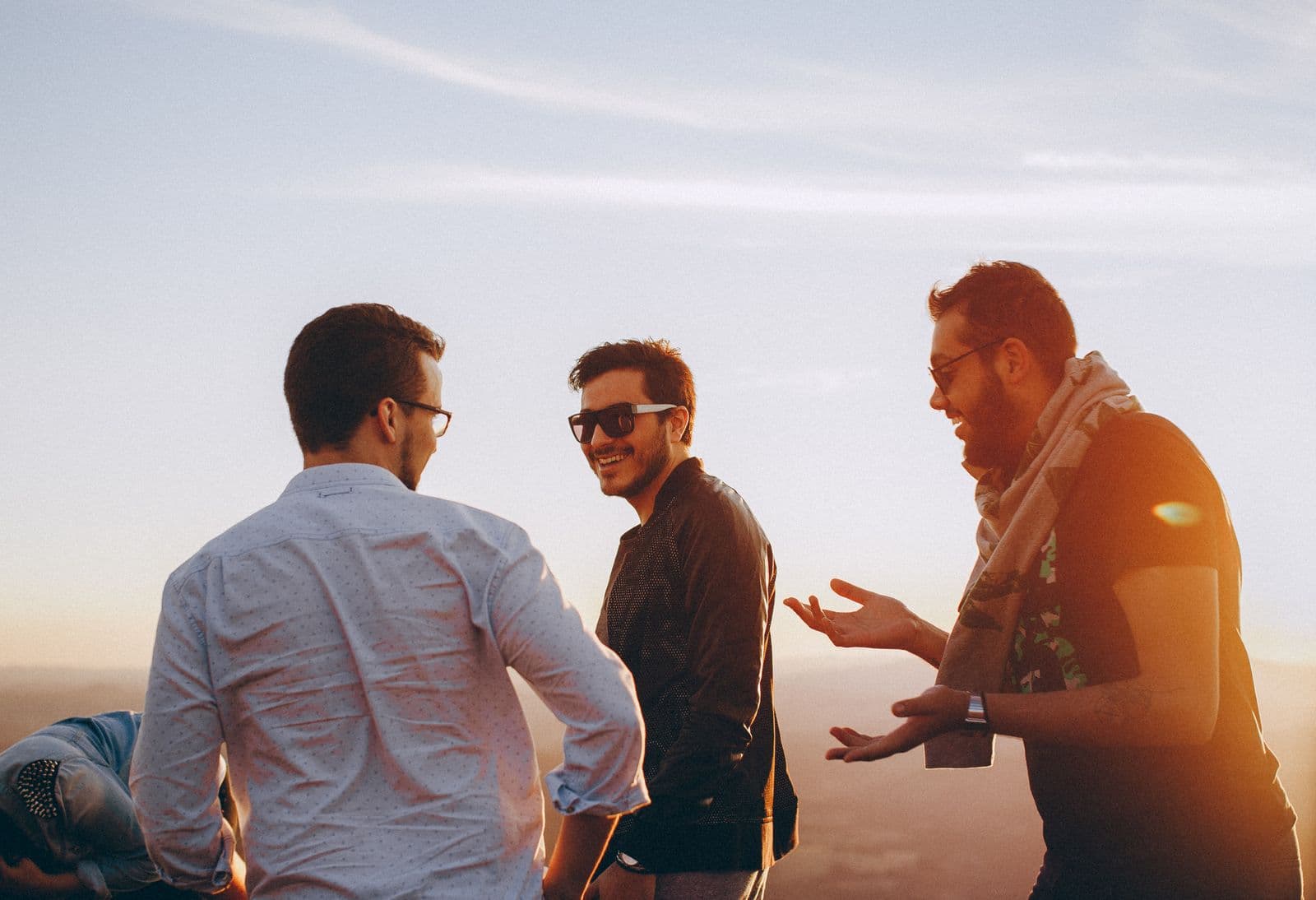 Friends talking and laughing together outdoors at golden hour