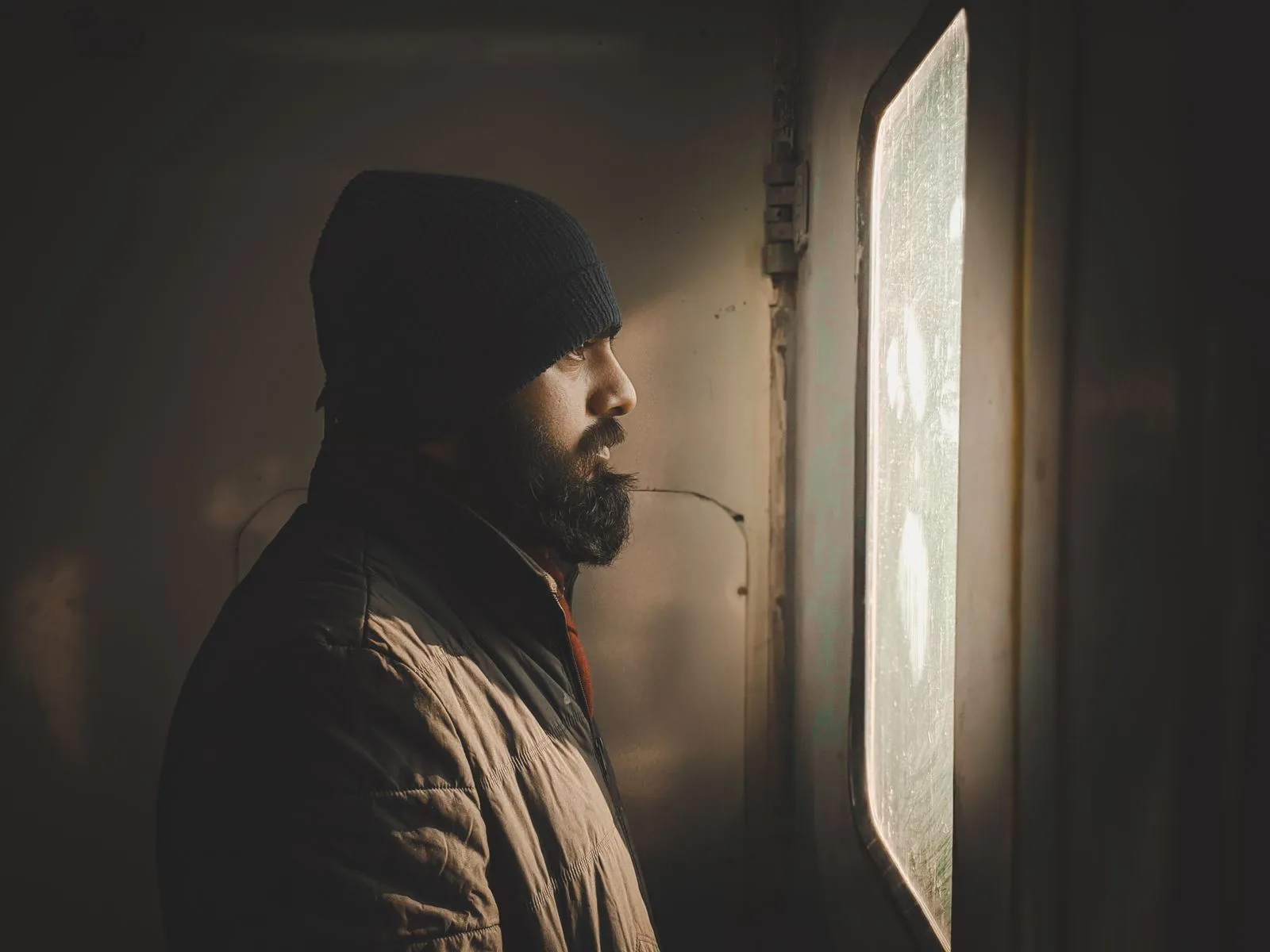 A man looking thoughtfully out of a window — loneliness often means feeling unseen, not simply being alone
