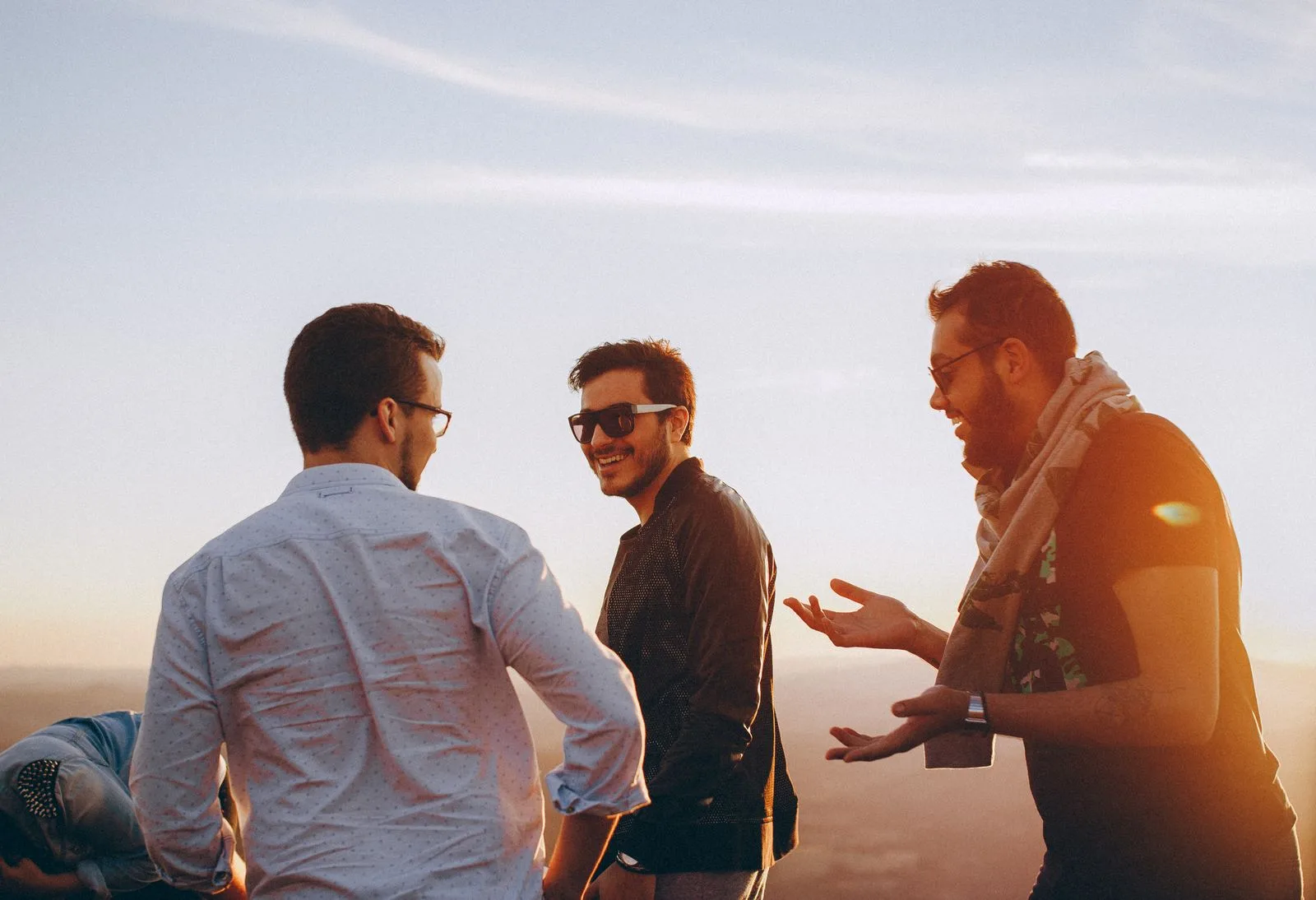 Friends talking warmly together outdoors at golden hour — connection is the antidote to loneliness