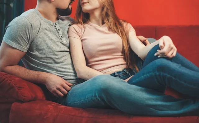 A couple sitting close together on a sofa, relaxed and connected