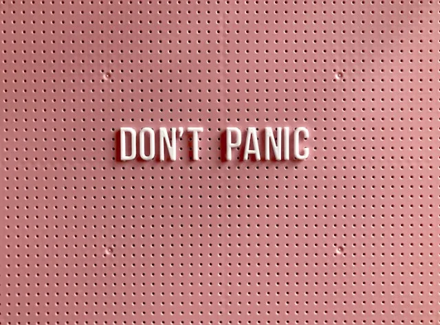 A reassuring reminder on a pink board reading "don't panic"